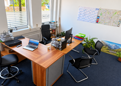 Arbeitsbereich im Büro der IN&D Team GmbH in München mit Schreibtisch, Computer und Besucherplätzen